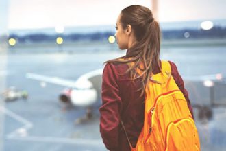 A woman observes an airplane, representing international student arrivals in Victoria.